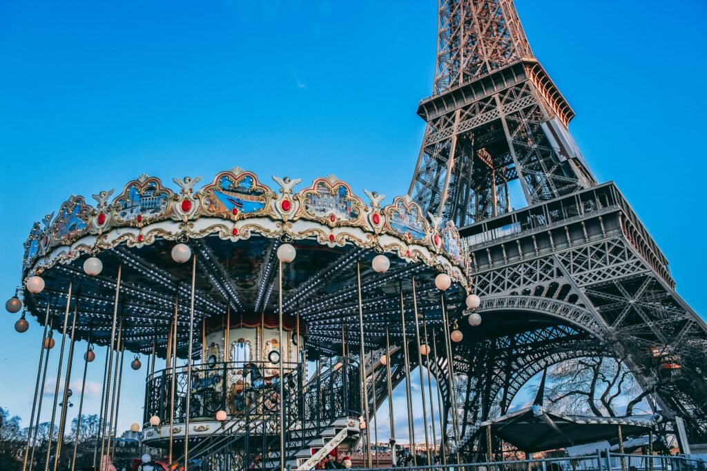 Eiffel Tower with a classic carousel in foreground on a bright day in Paris, France.